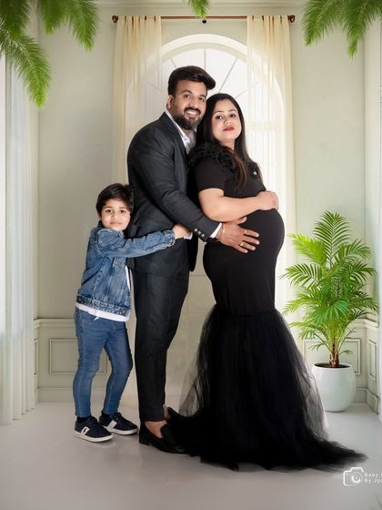 A full family portrait in the studio, with the older brother hugging his parents. It's a wonderful way to capture the family dynamic before the new baby joins.