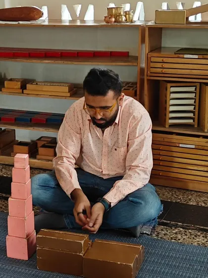 A father deeply focused on the iconic Montessori Pink Tower. In our Silent Journey workshops, parents work with the materials themselves to gain a profound, first hand understanding of their child's world of learning.