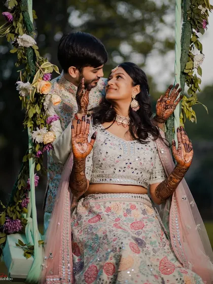 A sweet moment between Rishabh and Priya on the swing. The bride shows off her beautiful henna as they share a loving glance, a perfect candid couple portrait.