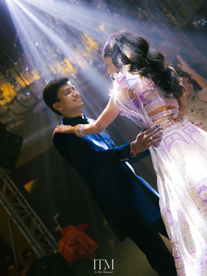Lost in the music and the moment. This candid shot from a sangeet captures the groom's loving gaze as they dance, surrounded by spotlights and the energy of the celebration.
