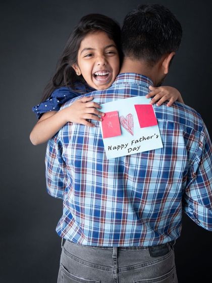 A Father's Day tribute! This photo beautifully captures a daughter's love for her dad, with a handmade card and a big, happy hug. These are the moments that truly matter.