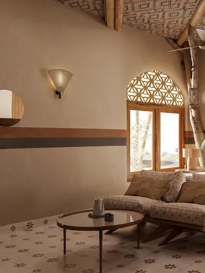 The wall in this room features bands of earthy color, adding a subtle decorative element. The latticed window, known as a *jali*, casts intricate patterns of light and is another nod to traditional Indian architecture.