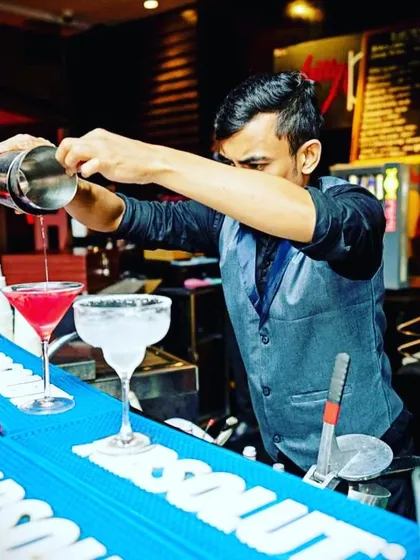 The art of the pour is central to what we do. This shot captures one of our mixologists carefully crafting a vibrant cocktail, showcasing the precision and attention to detail that goes into every single drink we serve.