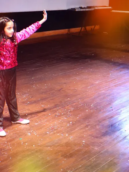 A young dancer is captured mid-move during a dynamic Bollywood performance. The stage lights and confetti add to the exciting atmosphere of our annual event.