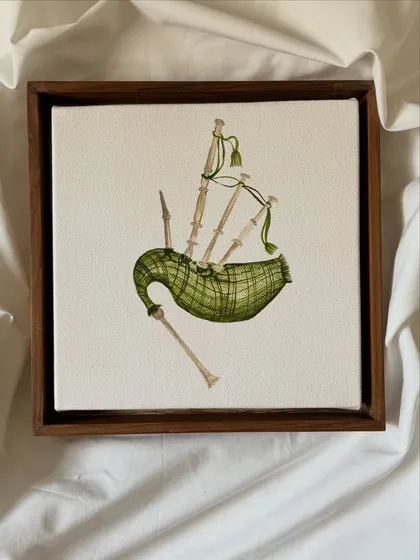 A detailed miniature painting of a set of bagpipes, showcasing the plaid pattern and intricate form of the instrument on a small canvas.