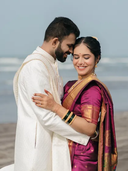 The beauty of a shared smile. This candidly styled portrait captures a moment of genuine happiness and comfort between the couple, set against the soft light of the beach.