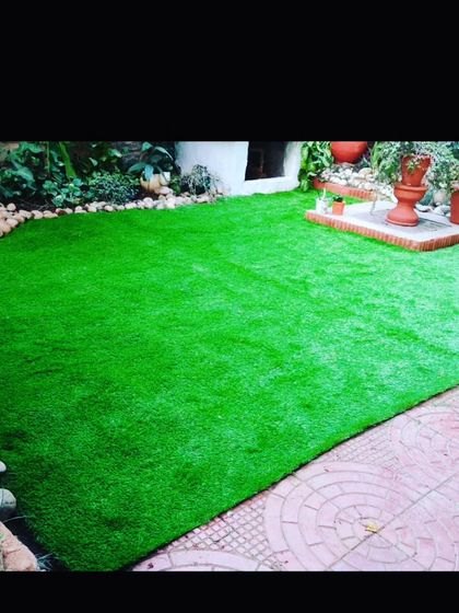 This garden area uses artificial grass bordered by natural stones and a tiled patio. I can work with existing landscapes to integrate new turf seamlessly.