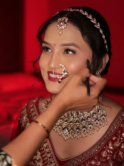 A candid moment during the makeup process, capturing the bride's beautiful smile.