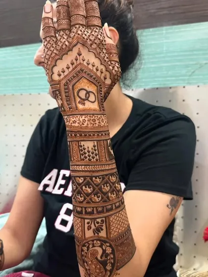 A beautiful design featuring a peacock on the forearm and a symbol of wedding rings on the palm.