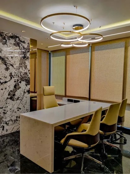 A wider view of an executive cabin at the Sun Group office. The space is designed for both work and meetings, with a clean, solid-surface desk and comfortable seating, all framed by a stunning view.