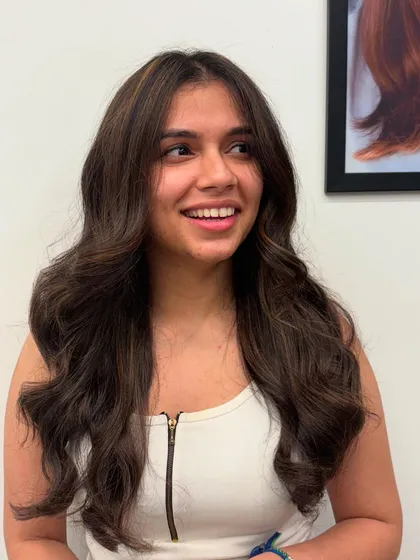 A candid shot of the client enjoying her new look. The face-framing highlights brighten her complexion.
