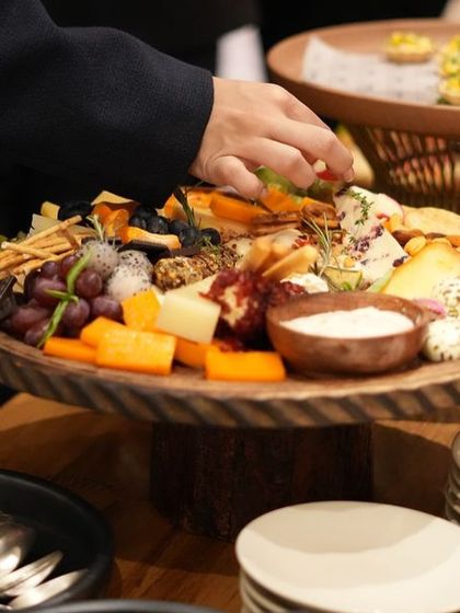 A guest helps themselves to our artisanal cheese and charcuterie board. We design our grazing tables to be interactive and inviting, encouraging guests to explore and enjoy.