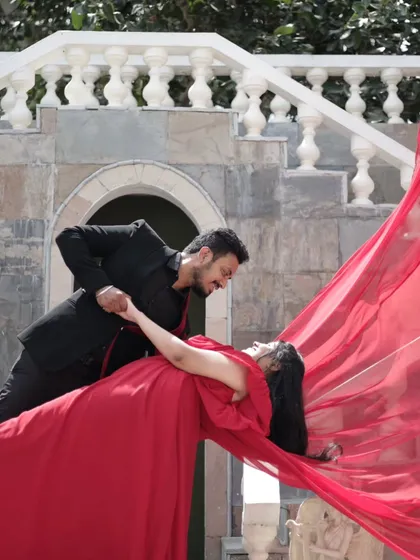 Creating a dramatic and romantic moment for a pre-wedding shoot. The bold red gown is complemented by classic makeup, ensuring the couple looks timeless and stunning in their photos.