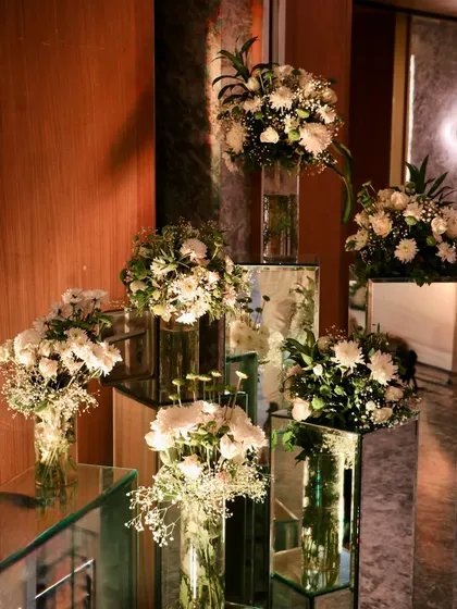 A stunning floral installation on mirrored pedestals, creating a modern and glamorous decor piece that reflects light and beauty.
