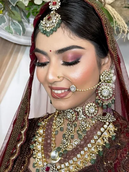 A soft and dreamy close-up of the bride. The shimmery pink eyeshadow and gentle smile capture a moment of quiet joy, highlighting the delicate artistry of her makeup.