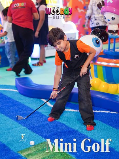 A young guest focuses on his shot at our indoor mini-golf course. This fun and engaging activity is a hit with kids and adults alike, adding a unique touch to any party.