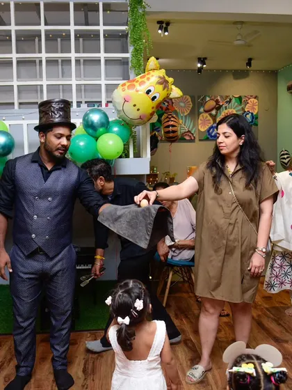 A parent volunteer helps the magician with a classic egg trick. The fun is for everyone!