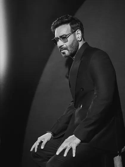 A seated black and white portrait that feels intimate and powerful, highlighting the sharp tailoring of the suit.