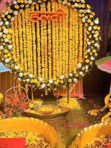 An outdoor Haldi setup with a large marigold floral ring as the centerpiece. The two urlis in the front are filled with turmeric and flower petals, ready for a fun-filled ceremony.