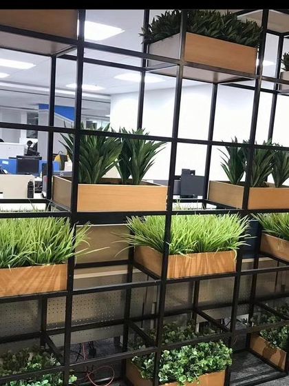 An office partition system made with a black metal frame and wooden planter boxes. I filled the boxes with different types of artificial grasses and plants to create a natural-looking divider.