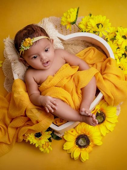 Heaven sent and picture-perfect. This awake baby looks right at the camera, her curious expression captured beautifully in this yellow floral setup.