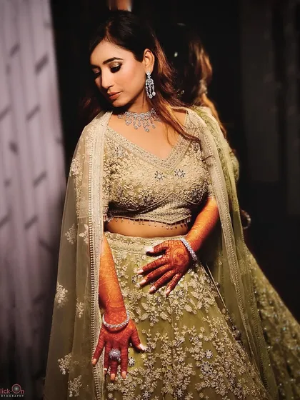 A reflective pose from the same indoor pre-wedding session. The mirror in the background adds depth to this portrait, highlighting the detailed embroidery on the light green lehenga.