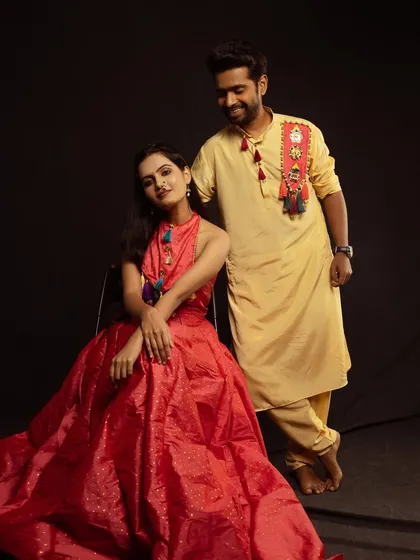 A playful and interactive couple portrait, with the man standing behind the seated woman, sharing a happy moment.