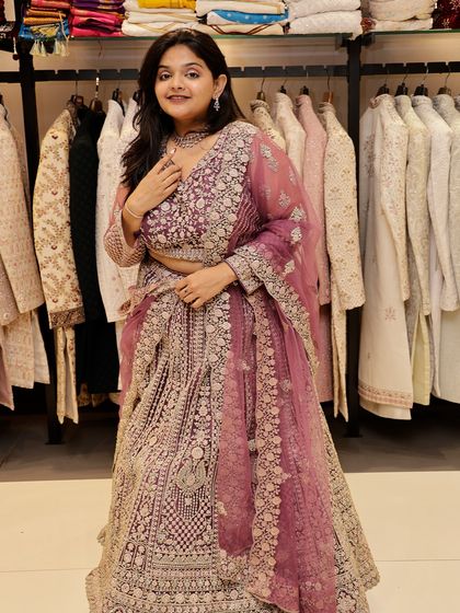 This is a full-length view of the mauve-pink embroidered lehenga. The craftsmanship is evident in the dense embroidery that covers the entire outfit, making it a luxurious rental option.