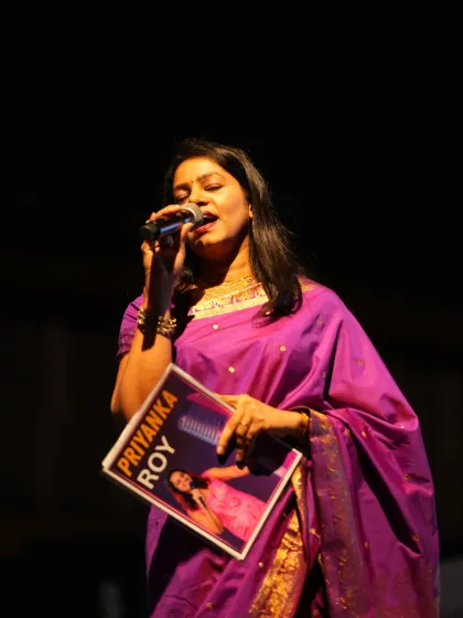 A moment of connection with the audience during a formal stage performance. Whether I am speaking or singing, I aim to create a captivating experience, holding a personalized folder to keep the event's proceedings organized.