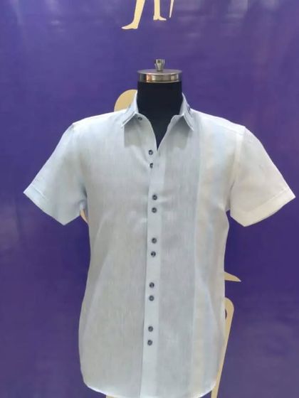 A simple yet elegant custom half-sleeve shirt. The light blue fabric with a central panel and contrast buttons makes it a great choice for a smart casual look.