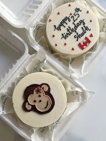 A set of two mini cakes for a 25th birthday and a cheeky friend. One has a Canadian flag, and the other features a cute monkey doodle.