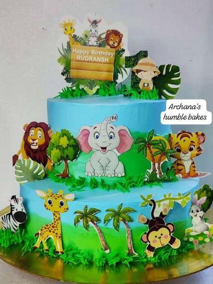 A two-tiered jungle safari cake for Rudransh's first birthday. It's decorated with cute, friendly animal toppers like elephants, lions, and monkeys.