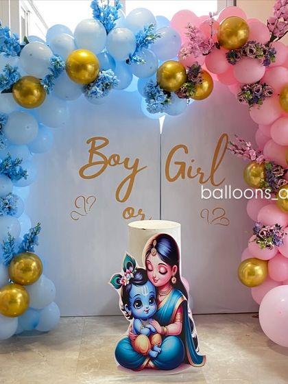 A closer look at the 'Boy or Girl' gender reveal backdrop, featuring adorable illustrations of baby Krishna and Radha.