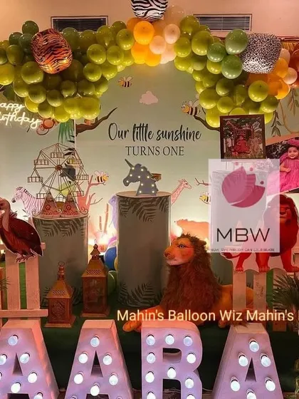 Another perspective of the jungle-themed first birthday, highlighting the custom backdrop and the mix of animal-print and solid-colored balloons in the arch.