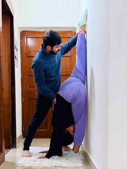 The standing split practice continues. My support at the hip and leg helps the student find more length and height in the pose.