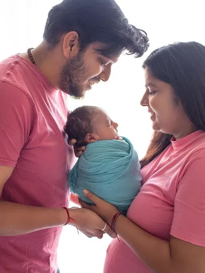 A loving gaze between new parents and their baby. The matching pink shirts and the baby's peaceful expression make this a very sweet family portrait.