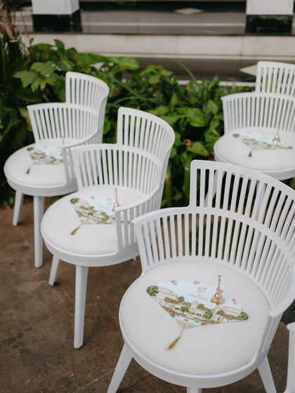 A playful detail from our "Tale as Old as Time" theme. These modern white chairs were customized with a printed fan on the seat, featuring illustrations that told the couple's story.