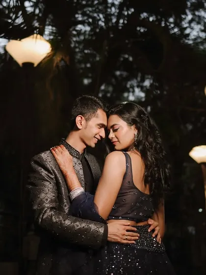 The couple shares a quiet embrace under a canopy of trees and hanging lanterns. This low-light shot creates a serene and romantic atmosphere, perfect for a pre-wedding night shoot.
