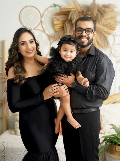 A happy family of three, all dressed in black. Their bright smiles and relaxed poses create a beautiful contrast against the earthy, boho-inspired studio set.