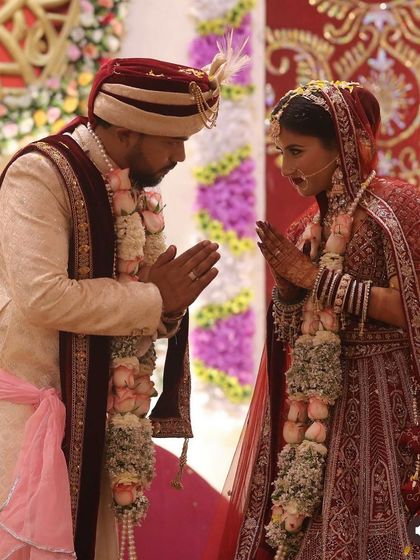 A sacred moment at the wedding ceremony. The bride and groom's coordinated red and cream outfits are a perfect match, and her soft, glowing makeup looks beautiful under the lights.