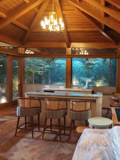 The interiors of the gazebo, still under wraps, show the warmth of the wooden structure. A statement chandelier and cozy rattan accent chairs await, ready to create an elegant and relaxing retreat.