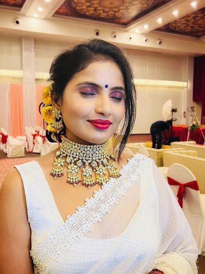 A close-up of the reception makeup, showing the blend of the smokey eyeshadow and the vibrant lip color. The yellow flowers in her hair add a beautiful, traditional touch.