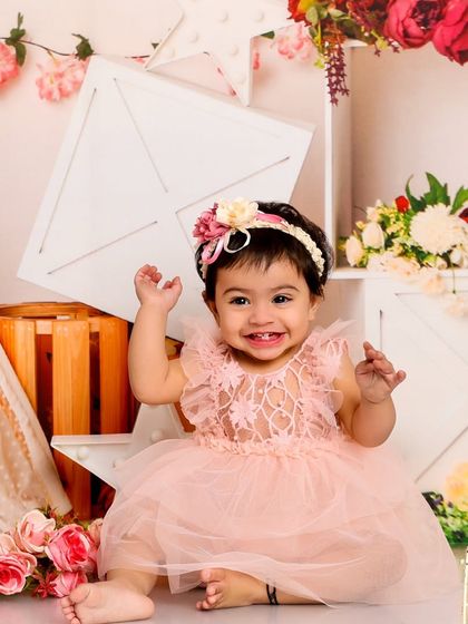 A beautiful, happy smile from this little girl in a pink dress. The floral and rustic props create a charming, shabby-chic vibe.