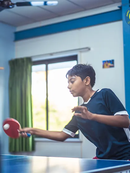 A young player is captured in action, focused on returning the ball. Our academy provides a great environment for junior athletes to develop their skills.