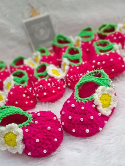 These strawberry-themed booties are so fun and fruity. They are made in a vibrant pink with green trim and a little white flower.