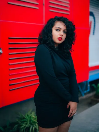 A duplicate of image 156, this portrait uses a vibrant red background to make the model in her black dress stand out.
