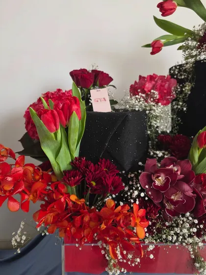 A close-up detail of the Neetu Singh Kapoor arrangement, focusing on the vibrant red tulips and the elegant, shimmering black gift box.