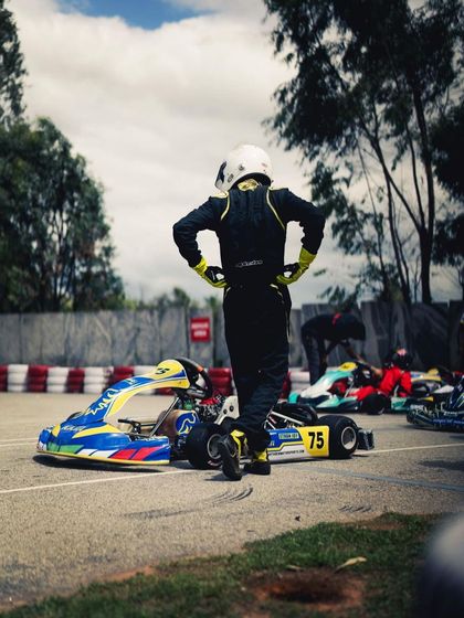 A driver stands by his kart, surveying the scene. After a challenging start to the weekend, his resilience and strategy paid off with a strong finish.