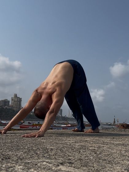 Adho Mukha Svanasana, or Downward-Facing Dog, with the Mumbai skyline in the background. This foundational pose stretches and strengthens the entire body and is a cornerstone of Vinyasa practice.