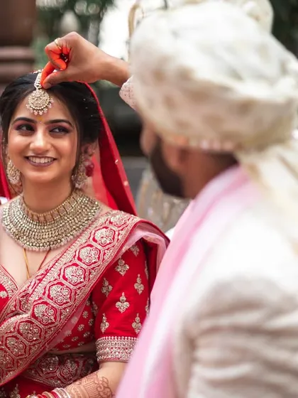 The groom applying sindoor to the bride's forehead, a significant ritual symbolizing their marriage.